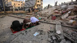 Tres hombres rezan en medio del caos tras un bombardeo israelí en Gaza