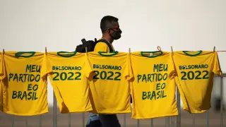 Un hombre camina junto a varias camisetas con lemas de apoyo a Bolsonaro