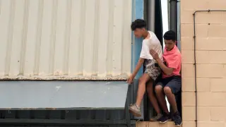 Dos chicos escapan de la nave del polígono industrial donde permanecen gran parte de los menores migrantes llegados a Ceuta.