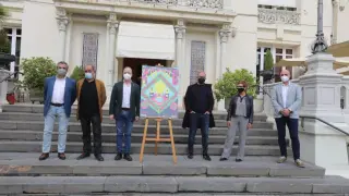 Representantes de las entidades que organizan y patrocinan el Festival de Cine de Huesca en la escalera del Casino junto al cartel de la edición de 2021