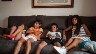 El niño saharaui Mohamed mira la televisión junto a Valentina, Germán y la pequeña Fabiola.