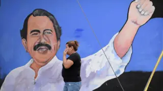 Una mujer pasa por un muro en el que está pintado Ortega.