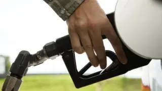 Una persona echando combustible en una gasolinera.
