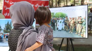 Una afgana ve una exposición en Kabul con fotos de conflictos bélicos.