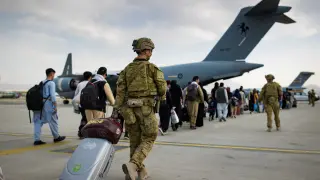 Australian citizens and visa holders prepare to board the Royal Australian Air Force C-17A Globemaster III aircraft, as Australian Army infantry personnel provide security and assist with cargo, at Hamid Karzai Internati