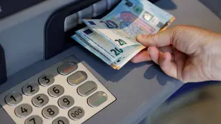 Una persona saca dinero de un cajero de una entidad bancaria.