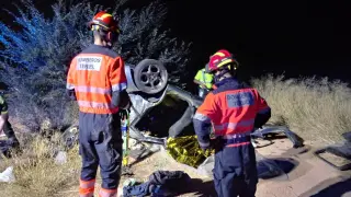Los Bomberos de Teruel, junto al vehículo volcado.