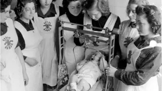 Jóvenes zaragozanas pesan a un bebé durante las prácticas del Servicio Social en 1944.