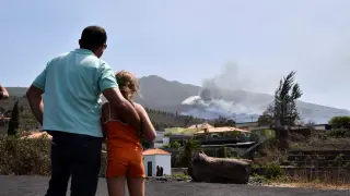 Un padre y su hija observan cómo la última colada toma contacto con la primera que emergió del volcán de Cumbre Vieja.