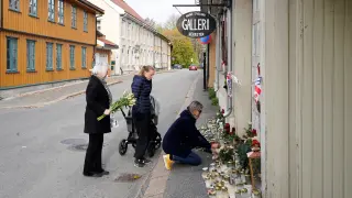 Algunos ciudadanos colocan flores y velas en el lugar donde murió una de las víctimas