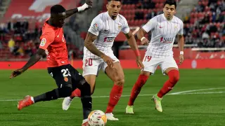 El delantero senegalés del Mallorca, Amath Ndiaye, disputa un balón con Diego Carlos y Marcos Acuña, defensas del Sevilla.