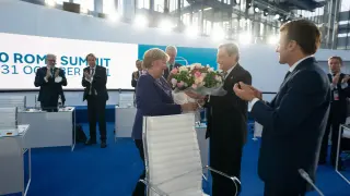 Momento en el que Merkel recibe las flores de manos de Draghi