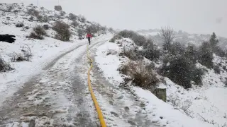 Un bombero, el domingo, lleva una manguera entre la nieve