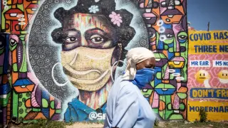 Una mujer pasa por delante de un mural que recuerda la pandemia en Johanesburgo