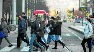 Una decena de personas cruza un paso de peatones en el paseo de la Independencia de Zaragoza, junto a las vías del tranvía.