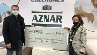 El presidente de Aspanoa, Gabriel Tirado, recibe el cheque solidario de manos de la gerente de Colchones Aznar, Carmen Cabeza.
