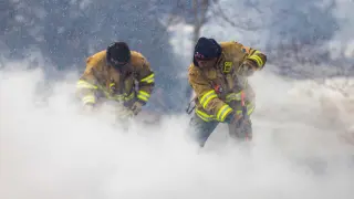 Los bomberos apagan un fuego el Louisville bajo la nieve.