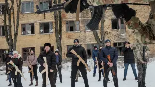 Varios civiles ucranianos hacen ejercicios con armas de la mano de un veterano militar, en la ciudad de Kyiv.