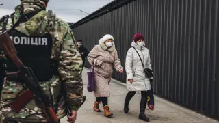 Dos mujeres caminan delante de un policía en el control fronterizo de Stanitsa Luganska para cruzar del territorio ucraniano al territorio de la autoproclamada República de Lugansk