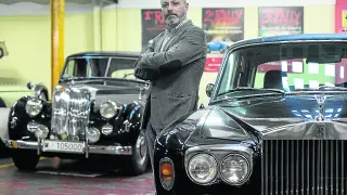 Raúl Aranda posa con varios coches clásicos en la tienda Imporauto, en Zaragoza.