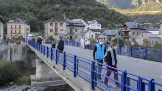Turistas atravesando el puente sobre el río Ara de Broto.