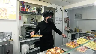 Soraya Ferrer prepara porciones de pizza en su establecimiento.
