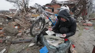 Una mujer mira recuerdos abandonados entre los escombros de una casa bombardeada en la ciudad ucraniana de Chernihiv