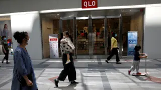 FILE PHOTO: FILE PHOTO: People wearing face masks walk past a store of Fast Retailing's fashion chain Uniqlo in Beijing