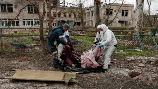 Cuatro personas trasladan un cadáver en Mariúpol