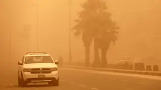 Un coche circula por una calle de Bagdad en medio de la tormenta de arena.