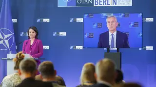 La ministra alemana de Exteriores, Annalena Baerbock, y en pantalla, el secretario general de la OTAN, Jens Stoltenberg.