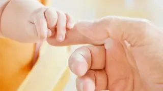 Un padre da la mano a su bebé.