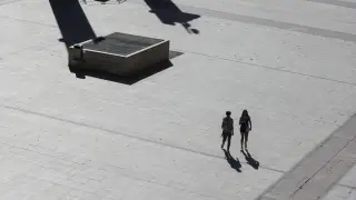 Dos personas caminan por una plaza del Pilar desierta por el calor