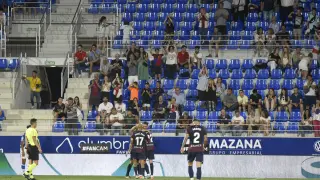 Los jugadores del Huesca celebran uno de sus tres goles ante la Real Sociedad B con una grada poco poblada al fondo.