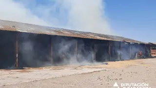 Los bomberos de la DPZ trabajan en sofocar un incendio en un almacén de paja de La Joyosa