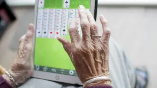 Foto de archivo de una anciana jugando a un juego en una tablet