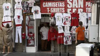 La dueña de un comercio del Casco Viejo de Pamplona coloca para su venta la ropa típica de los Sanfermines
