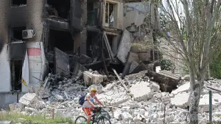 Un ciudadano circula en bicicleta ante las ruinas de un edificio destruido en Lisichansk