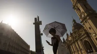Una mujer se protege del sol con un paraguas ayer tarde en la plaza del Pilar de Zaragoza
