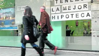 Dos ciudadanos pasean frente a un escaparate de una entidad bancaria.