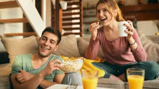 happy-couple-eating-popcorn-while-watching-movie-at-home