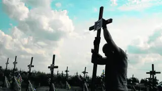 Un voluntario coloca el pasado agosto un cruz con un número en una tumba anónima entre enterramientos de asesinados por tropas rusas en Bucha.