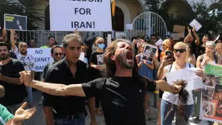 A demonstrator cuts his hair during a protest following the death of Mahsa Amini in Iran, in Nicosia,