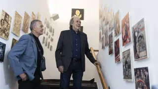 Agustín Sánchez Vidal y Joan Manuel Serrat contemplan una colección de pasquines de películas antiguas