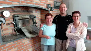 Antonio Mendiara y dos de sus tres hermanas, que atienden al público en el mostrador del horno de Ansó.