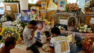 Varias personas rezan ante los féretros de algunos niños asesinados en la guardería tailandesa.