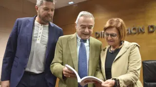 Alberto Sabio, Ángel Garcés y Maribel de Pablo ojean el libro ‘Huesca de cine’.