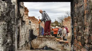 Varios voluntarios colaboran en la reconstrucción de las casas destruidas en el pueblo ucraniano de Novoselivka tras un ataque ruso.