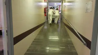 Varios celadores transportan a un paciente en su cama a través de una pronunciada rampa.
