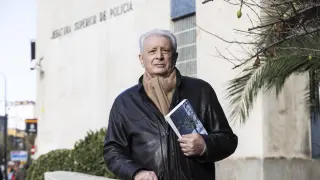 Luis Arrufat, exjefe de la unidad de Homicidios en la Policía Superior de Zaragoza, ante el edificio donde trabajó y con el ejemplar del libro 'Sala de espera' de Amazon.